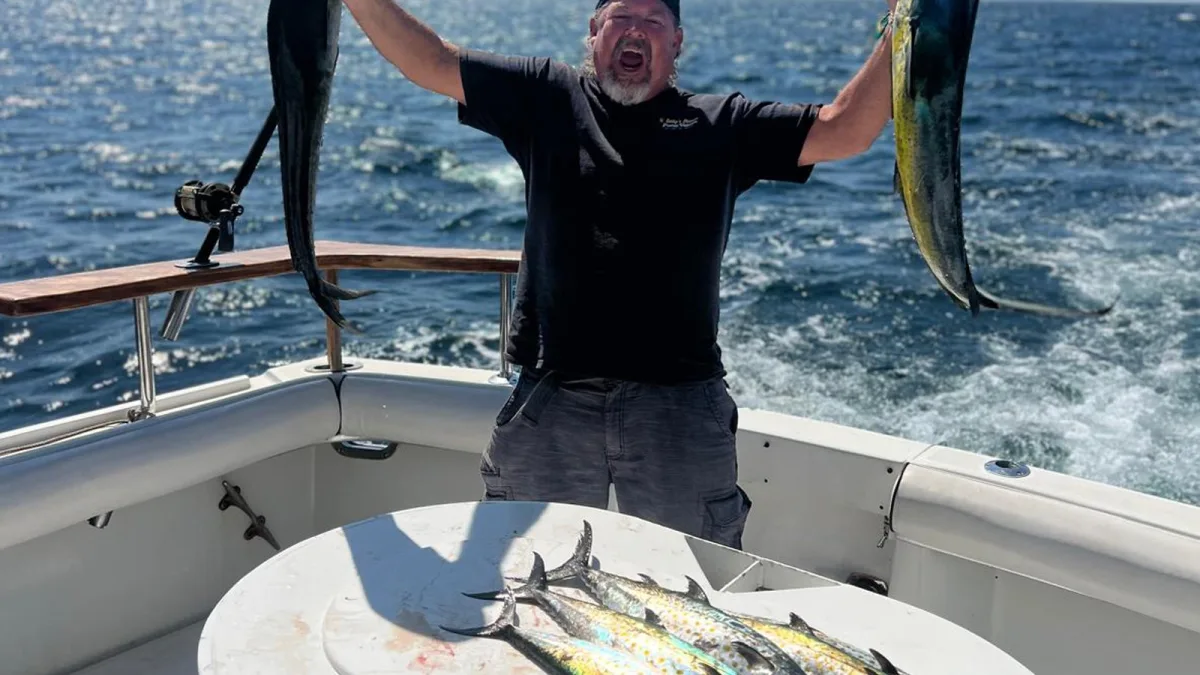 Un pescador levantando dos dorados a bordo de un charter de pesca deportiva en Puerto Vallarta