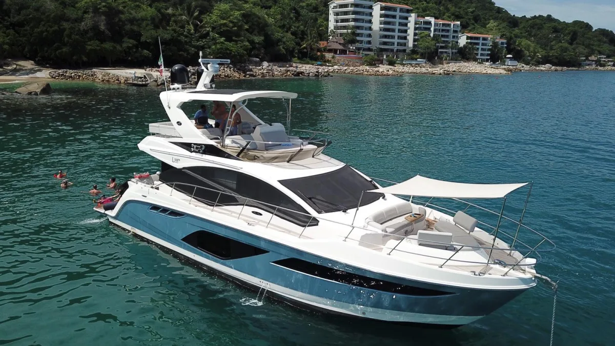 Un yate de motor fondeado bajo los acantilados al sur de Puerto Vallarta en un charter por la Bahía de Banderas