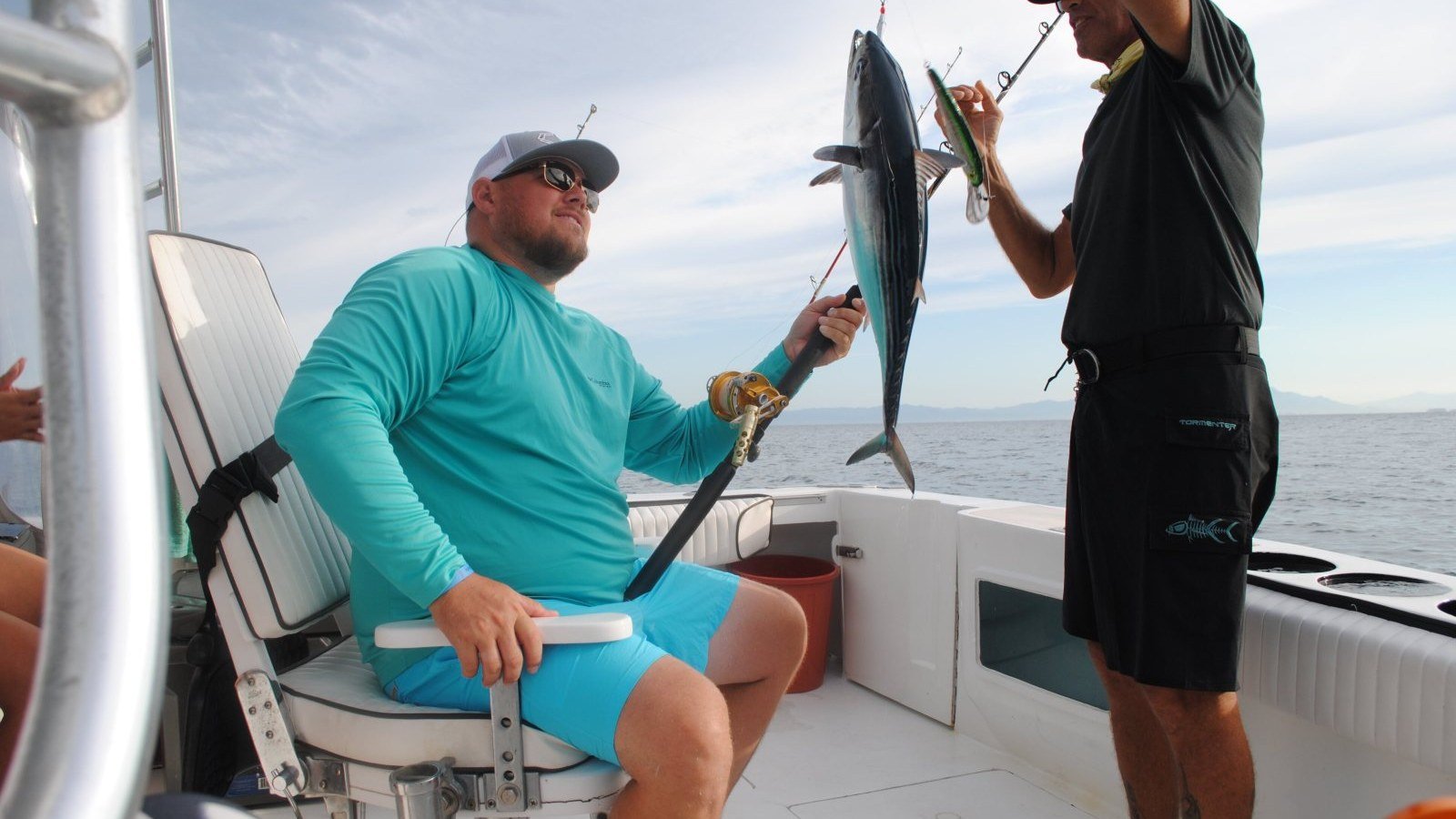 El marinero desengancha un bonito para un pasajero durante una salida de pesca en la Bahía de Banderas